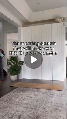 a man standing in front of a white wall next to a rug on top of a hard wood floor