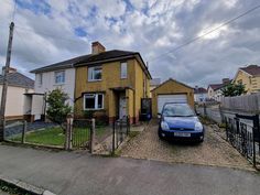 a blue car parked in front of a house next to a fence and gated yard