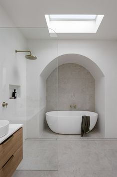 a large white bath tub sitting under a skylight