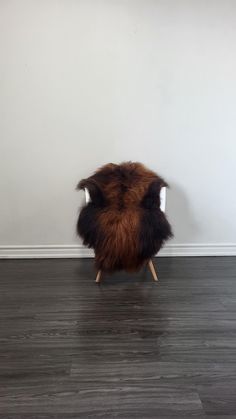 a brown and black chair sitting on top of a hard wood floor next to a white wall