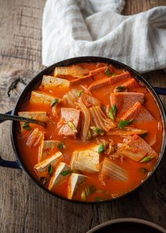 a pan filled with soup on top of a wooden table