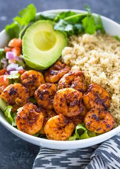 a bowl filled with shrimp, rice and avocado on top of a table