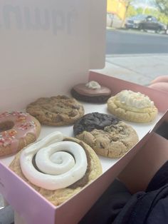 a pink box filled with different types of doughnuts