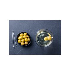 some olives in a bowl and two spoons on a table