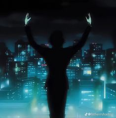 a person standing in front of a city at night with their hands up to the sky