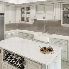 a white kitchen with marble counter tops and wine racks on the island in front of the sink