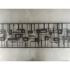 a metal wall sculpture with squares and rectangles on it's sides, mounted against a white wall