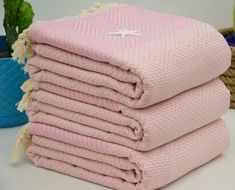 a stack of pink towels sitting on top of a table next to a potted plant