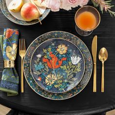 the table is set with plates, silverware, and flowers on black cloths