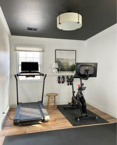 a home gym with treadmills, exercise bike and flat screen tv on the wall