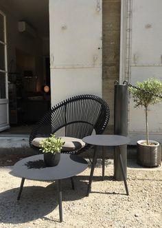 two black tables with plants on them in front of a building