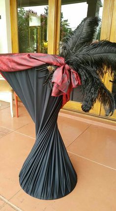 a black and red vase with a palm tree in it's center, sitting on a tile floor