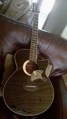 a guitar sitting on top of a brown couch