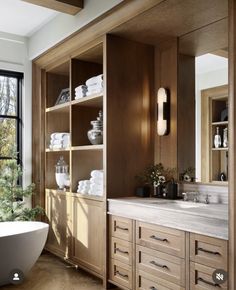 a bath room with a large tub and a sink in front of a big window