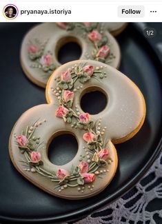 two decorated doughnuts sitting on top of a black plate