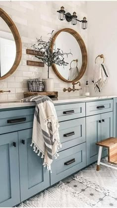 a bathroom with two round mirrors and blue cabinets