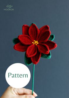 a crocheted flower being held by a person's hand with the word pattern below it