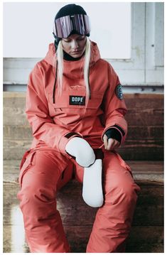 a woman in an orange jumpsuit is sitting down