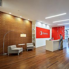 an office with wood flooring and red accent wall behind the reception desk, two people are standing at the counter