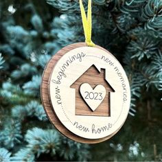 a wooden ornament hanging from a tree with a house and heart on it