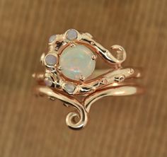 Octopus Glam Original Design Made in the USA This ring is inspired one of the most unique creatures of the sea. It features a 6 mm Australian opal that is AAA There are 5 other opals set into various suckers around the center stone. I have it shown in 14 karat gold and 14 karat rose gold. I can make with other stones also if you will like a different combination. There is also a unique coordinating band that can be worn alone or stacked with the engagement ring. I made this originally for a spec Octopus Engagement Ring, Whimsical Gold Wedding Rings, Unique 14k Gold Opal Ring, Unique Wedding Opal Ring, Fantasy Rings, Deer Rings, Leaf Wedding Rings, Unique Creatures, Octopus Ring