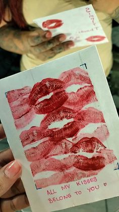 a person holding up a piece of paper with lipstick on it and writing all my kisses belong to you