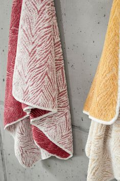 three towels hanging on the wall next to each other with different colors and patterns in them