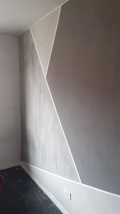 an empty room with a red chair in the corner and a wall painted gray, white and grey