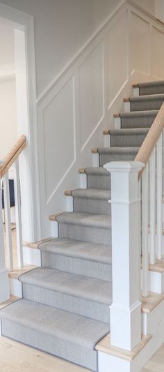 a white staircase with carpeted steps and handrails in a new build home