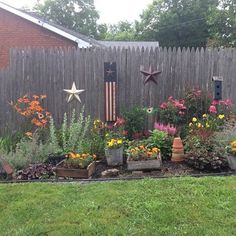 an outdoor garden with various flowers and plants in the foreground, next to a wooden fence