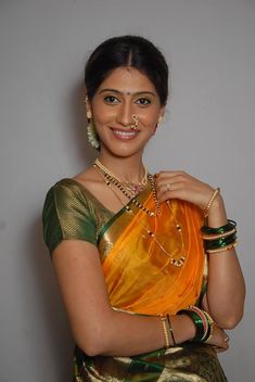 a woman in a yellow sari holding an orange purse