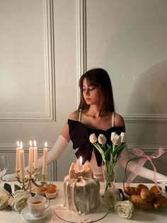 a woman sitting at a table in front of a cake with candles