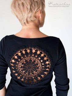 the back of a woman's black shirt with an intricate lace design on it