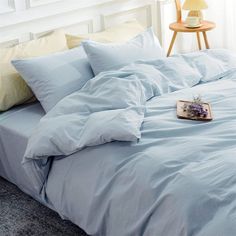 an unmade bed with blue sheets and pillows on the floor next to a lamp