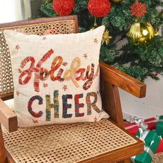 a pillow that says happy cheer on it sitting in a chair next to a christmas tree