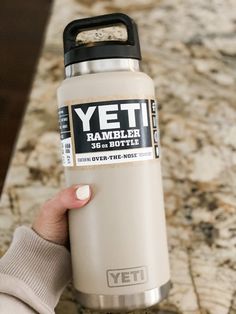 a person holding a yeti water bottle in front of a granite counter top with the words rambler on it