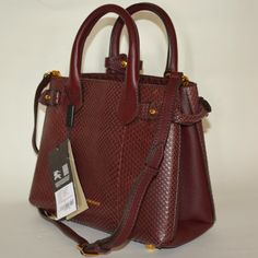 Authentic Burberry Python Leather Banner Derby Tote Bag Color: Mahogany Red New With Tags Made In Italy Retail: $3595 Rolled Top Handles With Keeper Strap, 4" Drop. Removable, Adjustable Shoulder Strap, 16" Drop. Open Top With Snap Closure. Belted Tabs Gather Sides Of Body. Logo Embossing At Bottom Center. Interior, Center Zip Compartment; One Zip And Two Slip Pockets. Canvas Lining. Metal Feet Protect Bottom. 10.2"W X 8"H X 4.5"D. Luxury Burgundy Shoulder Bag With Branded Hardware, Luxury Burgundy Crossbody Satchel, Formal Burgundy Bags With Branded Hardware, Luxury Burgundy Tote Satchel, Evening Burgundy Bag With Branded Hardware, Burgundy Evening Bag With Branded Hardware, Body Logo, Small Tote Bag, Small Tote