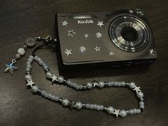 a camera is sitting on a table with beads and stars attached to the necklaces