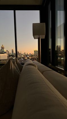 a couch sitting in front of a window next to a tall building with lots of windows