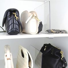 three different purses are on shelves in a display case, one is white and the other is black