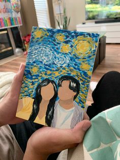 a person holding up a piece of art that looks like the starry night with two people