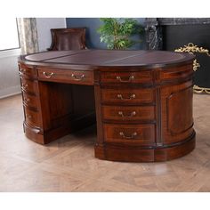 a large wooden desk sitting on top of a hard wood floor next to a potted plant