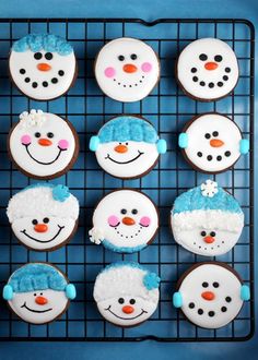 frosted cupcakes decorated with snowmen and hats on a wire cooling rack