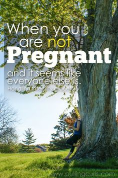 a woman sitting under a tree with the words, when you are not pregnant and it seems like everyone else is waiting