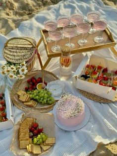 a table topped with lots of food on top of a white cloth covered beach area