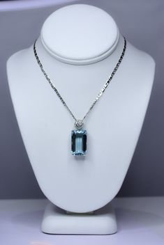 RRV: $17.650 A magnificent natural aquamarine pendant necklace features a large emerald cut aquamarine of 11.05 carats in a four-prong setting with gold design at the base. The bail is centred with a 3mm diamond and surrounded by a delicate halo of 16 diamonds.  The pendant is accompanied by a 50 cm length, 18 carats white gold chain. SPECIFICATIONS: 1982404 Gemstone: Emerald-cut natural Aquamarine. Measures: 16.67 x 9.97 x 8.03. Weight: 11.05 carats. Side Stones:  *1 x 3.0mm round brilliant cut Luxury Elegant Solitaire Gemstone Necklace, Luxury Classic Necklace With Rectangular Stone, Luxury Aquamarine Necklace In Fine Jewelry Style, Luxury Aquamarine Pendant Necklace, Light Blue Emerald Cut Fine Jewelry, Luxury Aquamarine Jewelry With Diamond Accents, Luxury Aquamarine Necklace For Formal Occasions, Elegant Light Blue Aquamarine Necklace, Light Blue Fine Jewelry Necklace For Formal Occasions