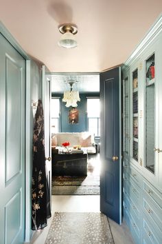 a hallway leading to a living room with blue walls and white trim on the doors