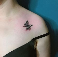 a woman's chest with a small butterfly tattoo on the left side of her upper arm