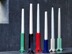 five candles are lined up in different colors and sizes, with one white candle sticking out of the middle