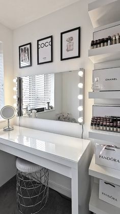 a white vanity with lights on it in front of a mirror and some pictures above it